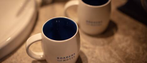 Dos tazas blancas con interior azul sobre una encimera.