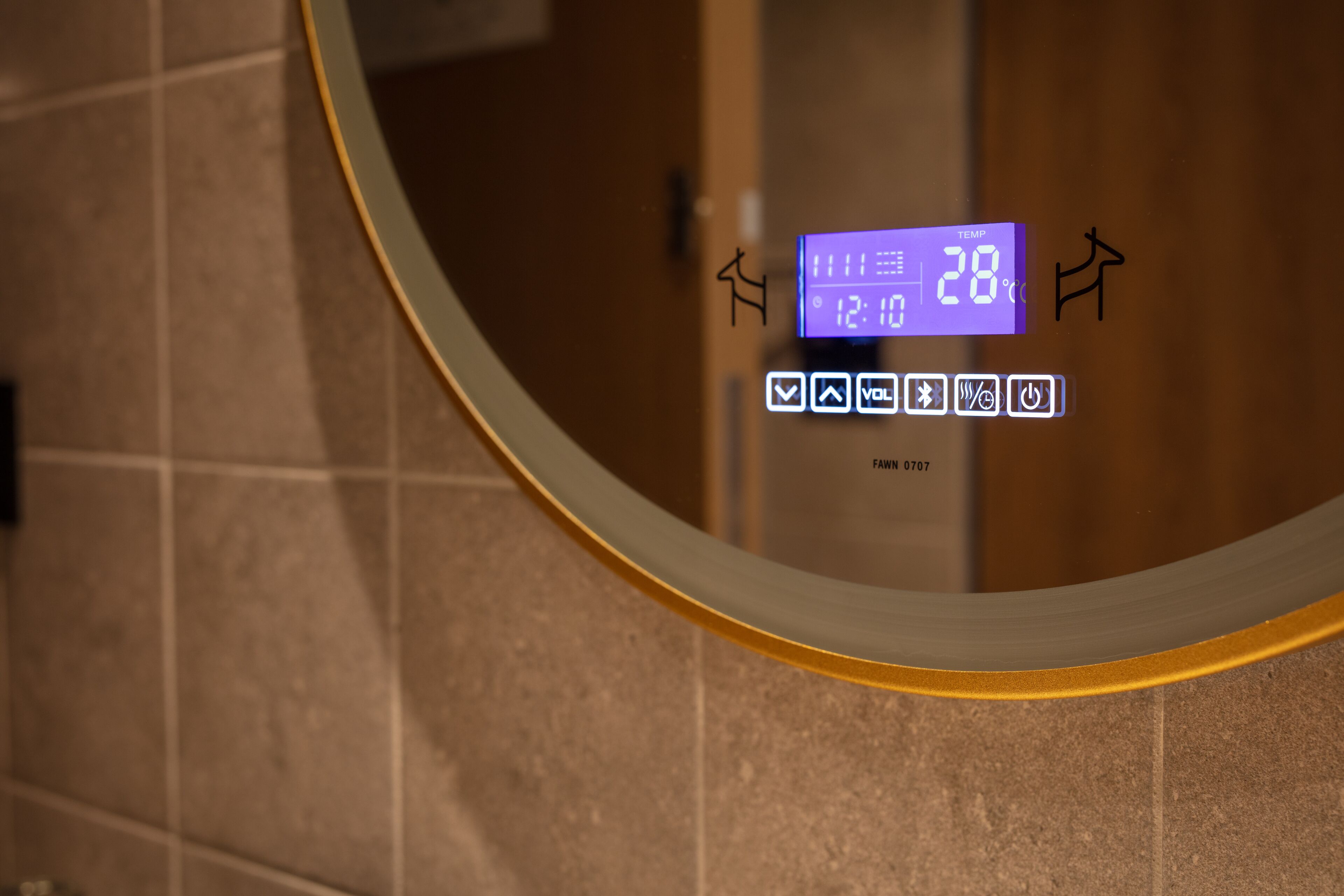 Un baño con una pantalla digital que muestra la temperatura en 28°C y la hora, 12:10.