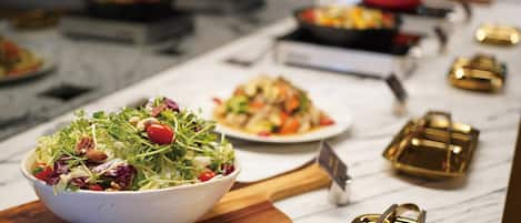 Montaje de bufé con diversos platos, incluyendo un bol de ensalada y un plato de comida, sobre una encimera de mármol.