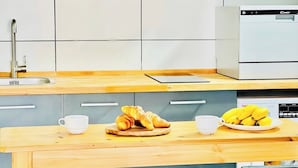 Una cocina moderna con encimera de madera, un fregadero, lavavajillas y cafetera.