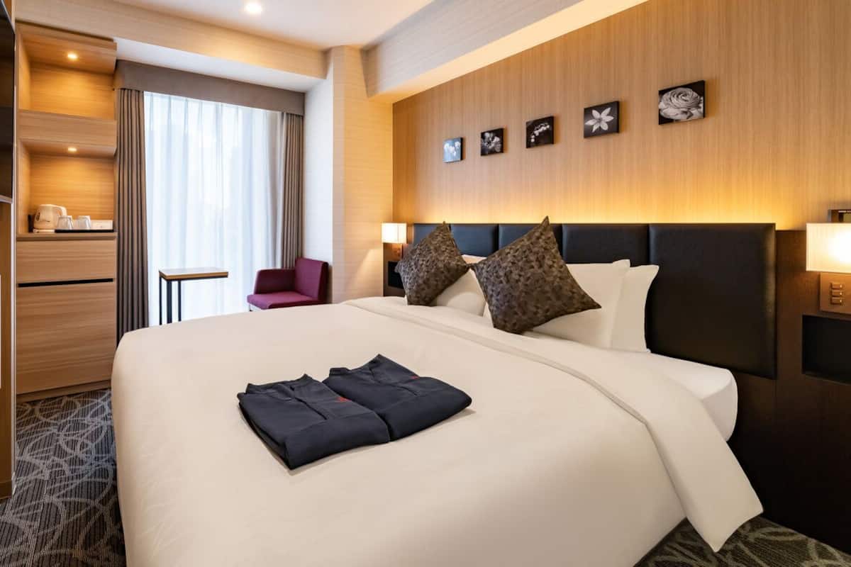 A hotel room with a large bed, a TV, a desk, and a chair.