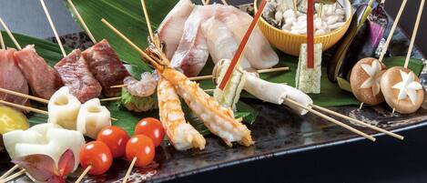 A variety of skewered seafood and vegetables on a black plate.