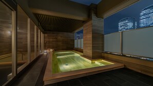 A modern spa area with a heated floor, wooden walls, and a city view. - HOTEL SHURANZA MAKUHARI BAY (Chiba)