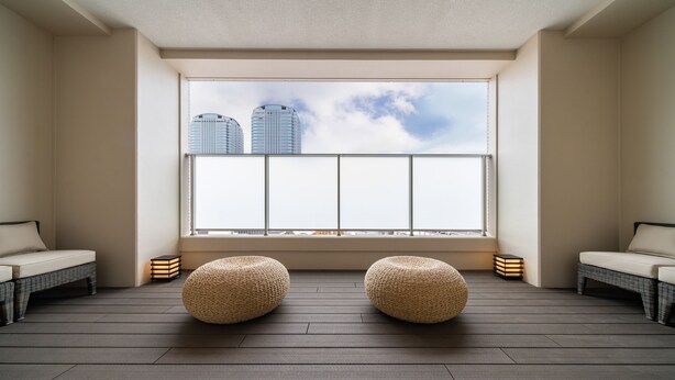 A room with a large window, two wicker poufs, and a view of tall buildings. - HOTEL SHURANZA MAKUHARI BAY (Chiba)