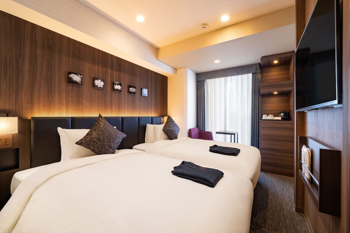 A hotel room with a large bed, a wooden headboard, a flat-screen TV, and a desk with a chair.