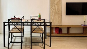 Un espace repas comprenant une table en verre, des chaises en métal noir et un banc en bois.