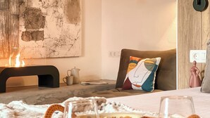 A cozy room with a bed, a bedside table with a lamp, a wall art piece, and a pillow with a colorful design. - Canaryislandshost l The Sky Suites (Tinajo)