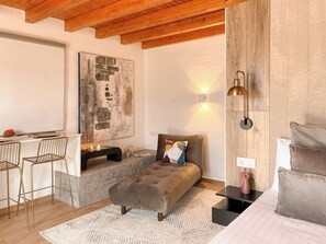Una habitación acogedora con techo de madera, un cuadro abstracto grande, un sofá, una mesita pequeña y un escritorio con sillas.