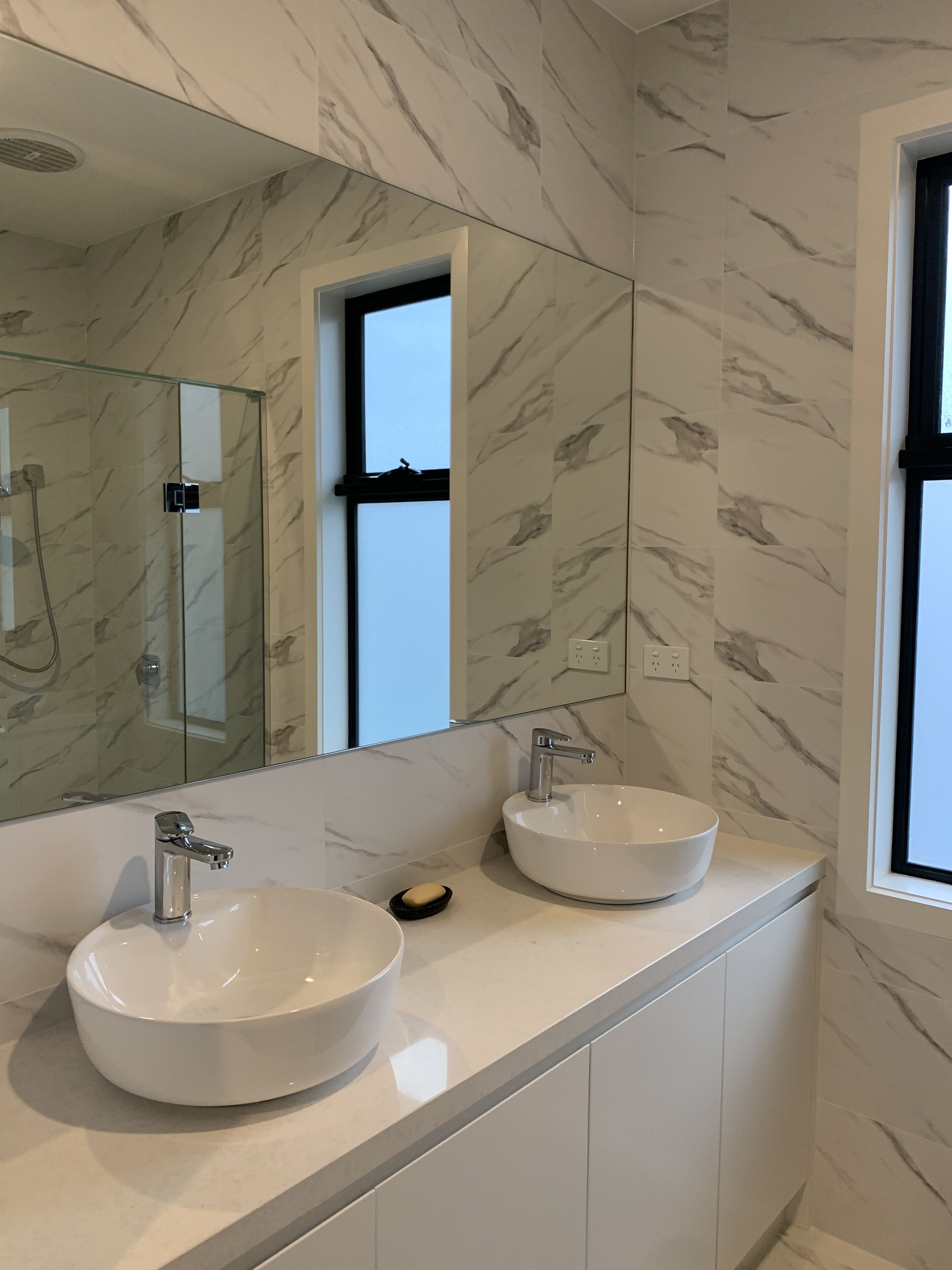A bathroom with two sinks, a glass shower enclosure, and a large mirror.