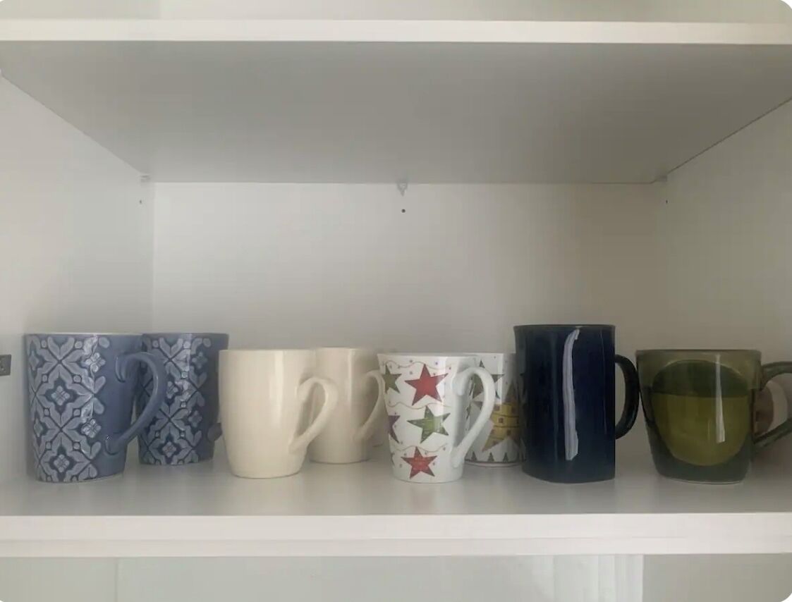 A shelf with five mugs of different designs and colors.