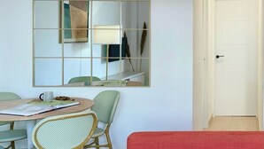 Ein Zimmer mit einem runden Esstisch, grünen Stühlen, einem roten Sofa und einem großen Spiegel an der Wand.