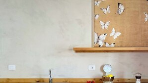 Eine Küche mit Holzausstattung, einer Edelstahlspüle, einer Kaffeemaschine und einem Wandregal mit Schmetterlingen.