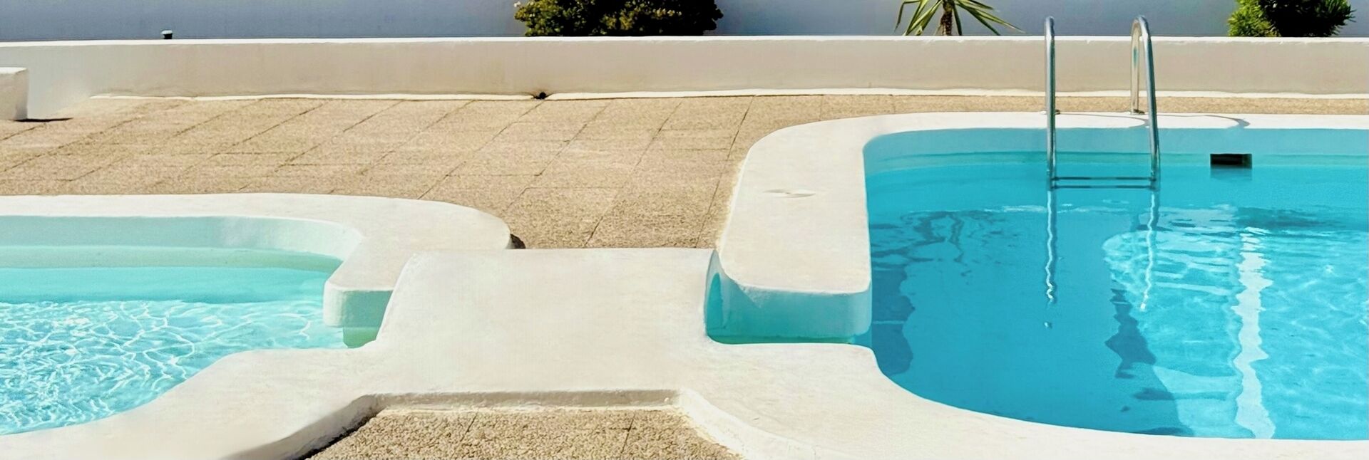 A pool with two separate sections, one larger and one smaller, with a clear view of the water.