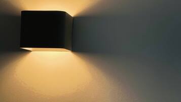 A wall-mounted light fixture casting a warm glow on a plain wall.