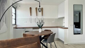 Una cocina moderna con armarios blancos, una mesa de comedor de madera y una lámpara colgante.