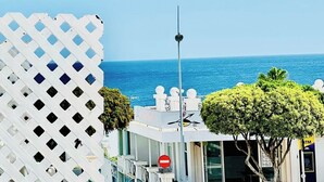 A coastal view with a white lattice fence, a no entry sign, and a building with a view of the sea. - Canaryislandshost l Mar Lanzarote (Puerto del Carmen)