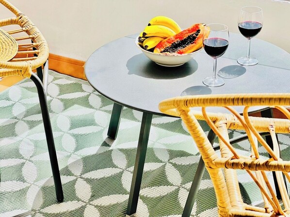 A round table with a bowl of fruit and two wine glasses.