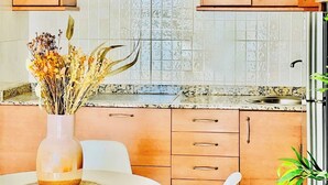 A kitchen with wooden cabinets, a tiled backsplash, and a vase with dried flowers on the countertop. - Canaryislandshost l Mar Lanzarote (Puerto del Carmen)