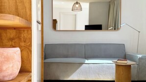Un salon moderne avec un canapé gris, une table basse en bois et un grand miroir au mur.
