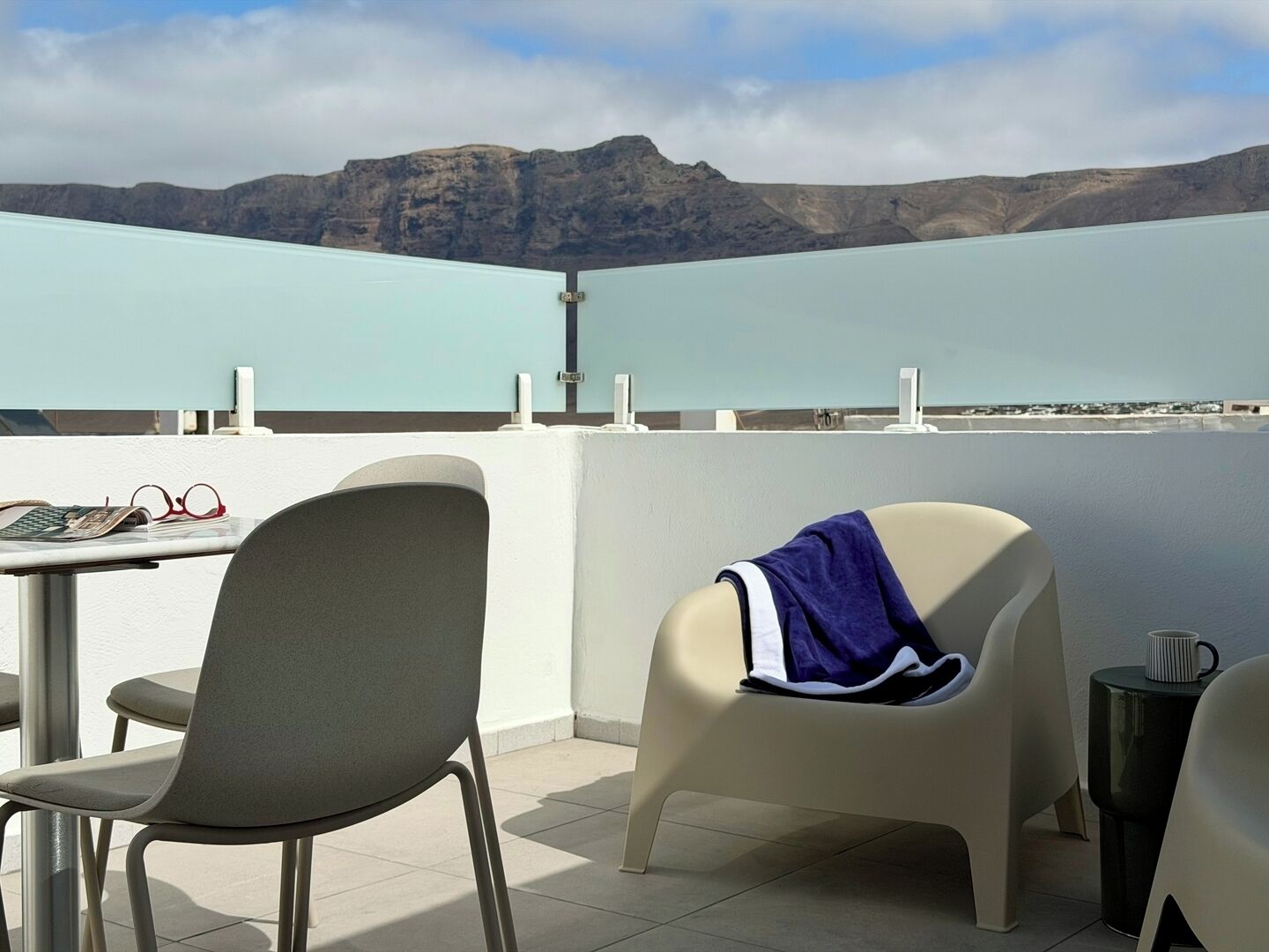 Un balcón con una mesa, sillas y vistas a las montañas.