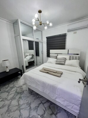 Un dormitorio moderno con una cama grande, una mesita de noche, un espejo y una lámpara en el techo.