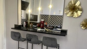 Een moderne keuken met een grote spiegel, barstoelen en decoratieve wandkunst.