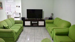 A living room with green sofas, a flat-screen TV, and a white cabinet. - Canastra Ebenezer House in Vargem Bonita, MG (Vargem Bonita)