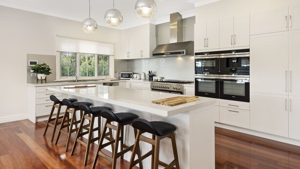 Una cocina moderna con una isla grande, electrodomésticos de acero inoxidable y taburetes de bar.
