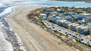 Een kustgebied met woonhuizen direct aan het strand, een promenade en een parkeerplaats.