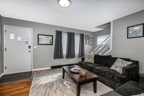 Un salon moderne avec un canapé gris foncé, une table basse en bois et un tapis à motifs.