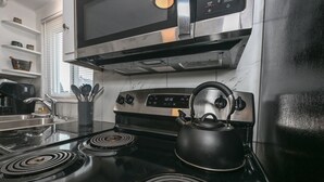 Una cocina con estufa, hervidor y microondas.