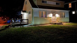Una casa de dos pisos con porche delantero, cochera y puerta principal bien iluminada.