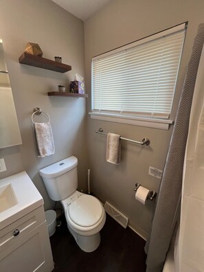 Une petite salle de bain comprenant des toilettes, un bidet et une fenêtre avec des stores.