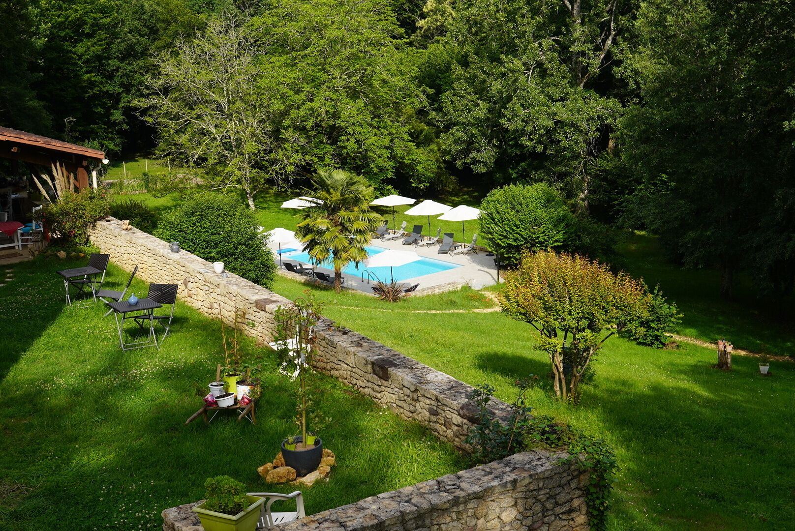 A backyard with a swimming pool, stone wall, and outdoor seating area.