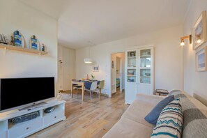 Una sala de estar con televisor, zona de comedor y sofá.