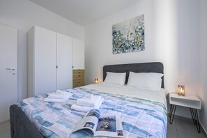 A neatly made bed with a magazine, a white bedside table with a lamp, and a large abstract painting on the wall. - Casa Palma, Lugano, Switzerland (Lugano)