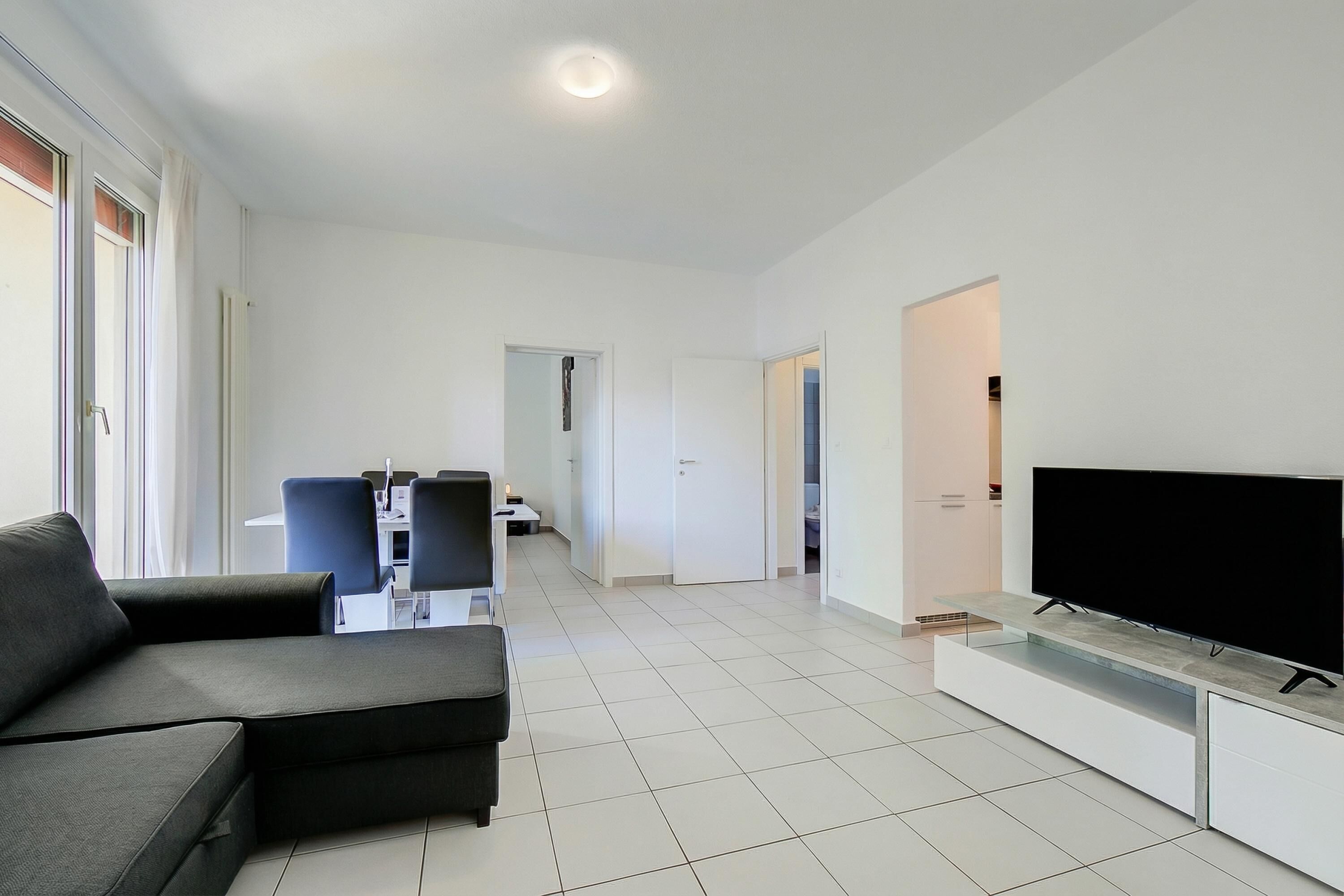 Una sala de estar moderna con un sofá, televisor y sillones.