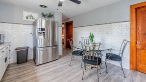 Eine moderne Küche mit einem Edelstahl-Kühlschrank, einem Glastisch mit Metallstühlen und einem Deckenventilator.