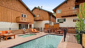 A pool area with wooden buildings, outdoor seating, and a clear sky. - Alpenblick 09 (Aspen)