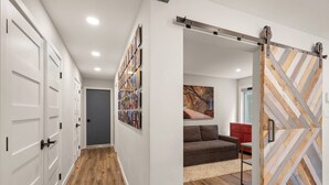 Un couloir avec des portes blanches, un plancher en bois et un mur orné de plusieurs tableaux encadrés.