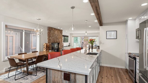 Une cuisine moderne dotée d’un grand îlot central, de planchers en bois et d’un mur d’accent en pierre.