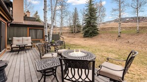 Une terrasse extérieure dotée d’un foyer, de sièges et offrant une vue sur le paysage environnant.
