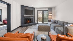 Un salon moderne avec une cheminée, un canapé, des fauteuils en cuir et un téléviseur à écran plat.