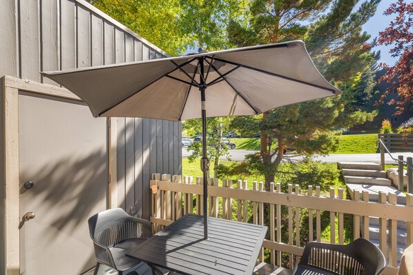 Un patio con una mesa, sillas, una sombrilla grande y una valla de madera.