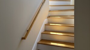 A staircase with wooden steps and a gold handrail, leading to a landing with a window. - Luxury stay  at 4 bedroom house (Florence)
