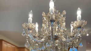 A chandelier with multiple lights and crystal decorations in a kitchen with wooden cabinets and a central island with bar stools. - Luxury stay  at 4 bedroom house (Florence)