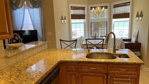 A kitchen with granite countertops, wooden cabinets, a built-in dishwasher, and a large island with a sink. - Luxury stay  at 4 bedroom house (Florence)