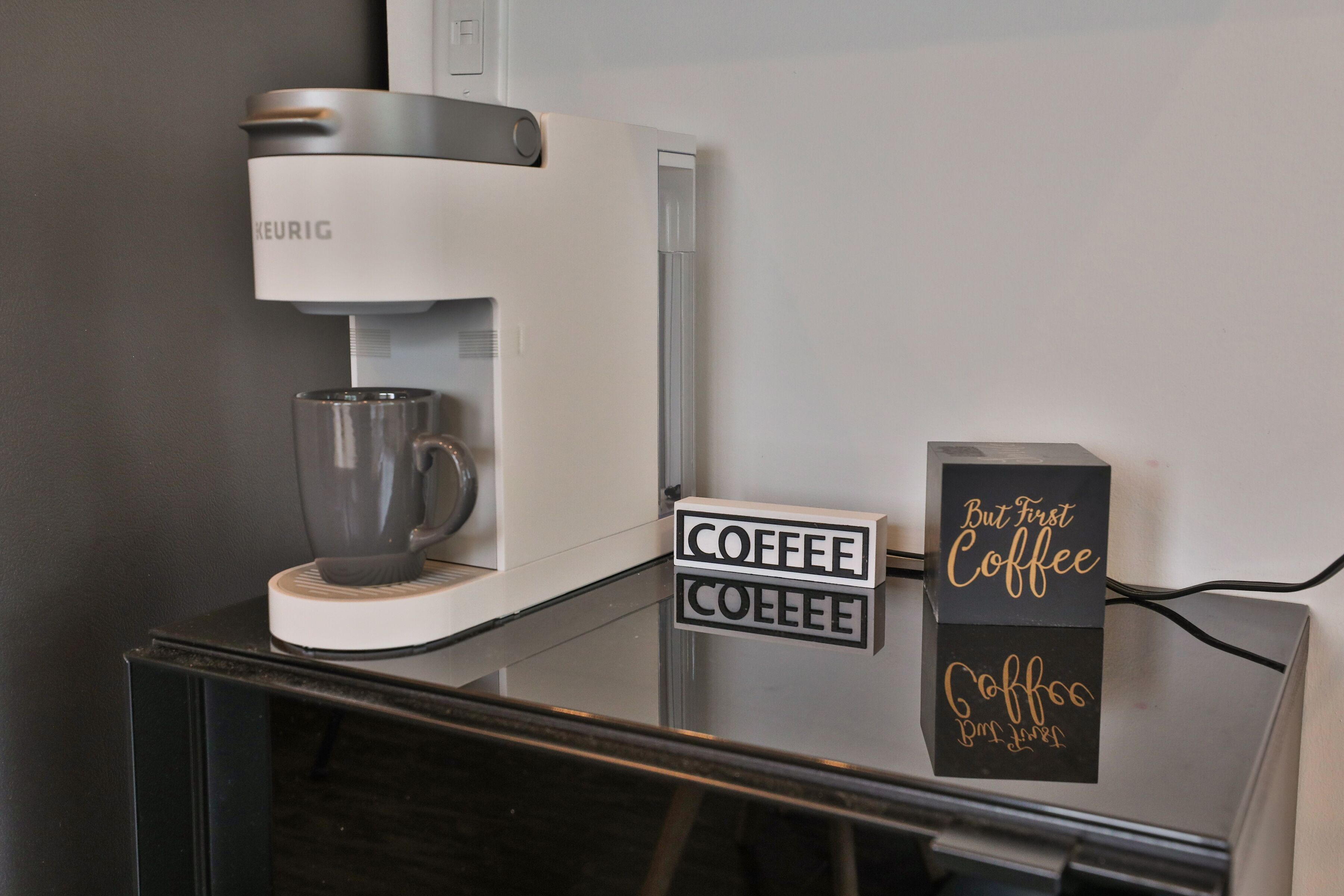 Eine Kaffeemaschine mit einer Glaskaraffe und einem Schild, auf dem 'Coffee Coffee Coffee' steht.