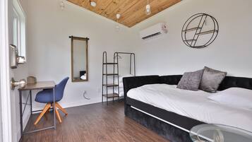 A bedroom with a bed, a desk, a chair, a ladder, and a mirror.