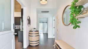 A hallway with a wooden barrel, a bench, a mirror, and a welcome sign. - Modern & Comfy ~ 5 Star Location in EaDo ~ King Bed ~ Parking! Pet Friendly! (Houston)